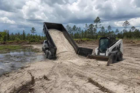 Clean fill dirt being spread and compacted in controlled lifts on a prepared site