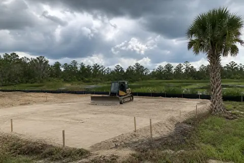 Compact grading machine shaping sandy ground for positive drainage